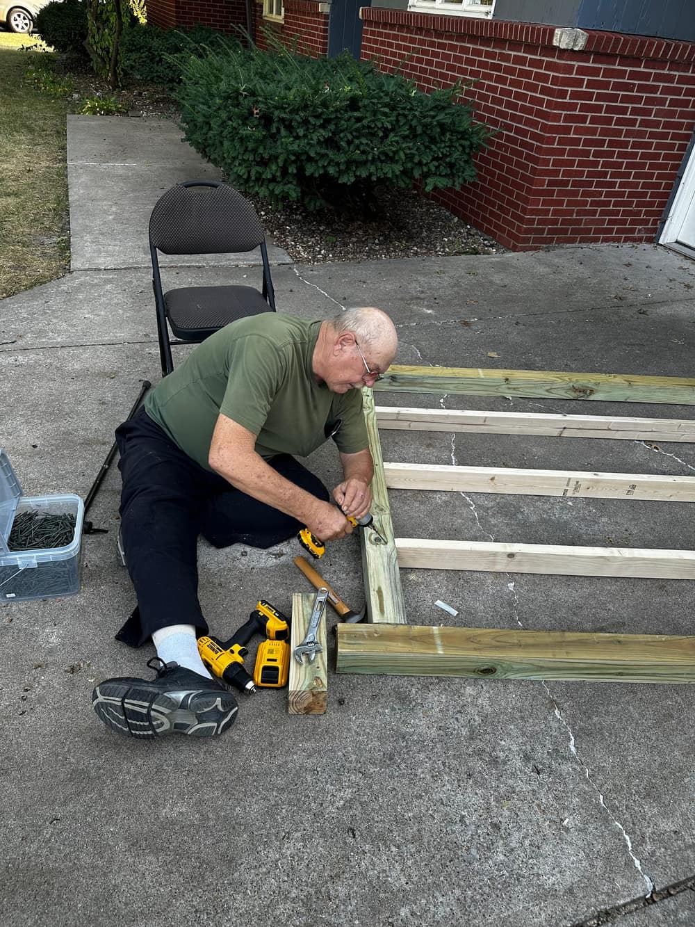 Ben's dad, seated, driving screws into the frame.