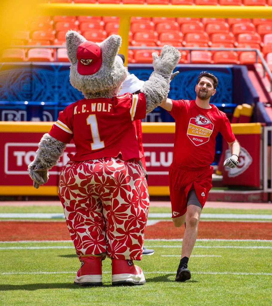 Ben in his red Fantasy Camp jersey running onto the field and high-fiving the Chiefs mascot, KC Wolf.