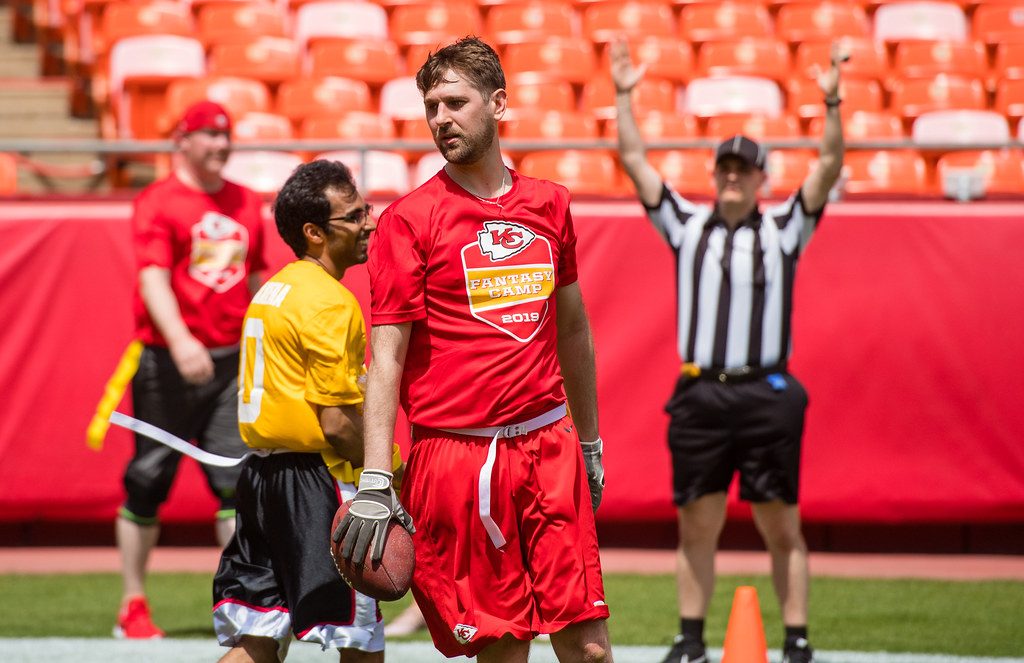 Ben in his red Fantasy Camp jersey holding the football in the end zone as the referee raises both arms to signal a touchdown.